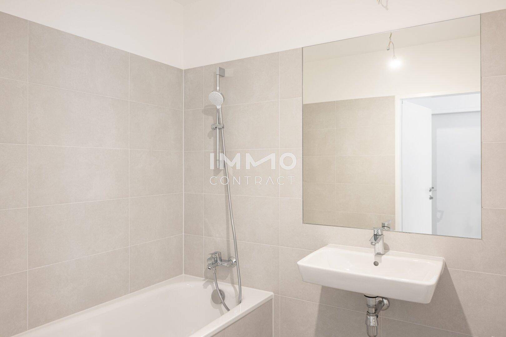Modernes Badezimmer mit Badewanne, Waschbecken und großem Spiegel.