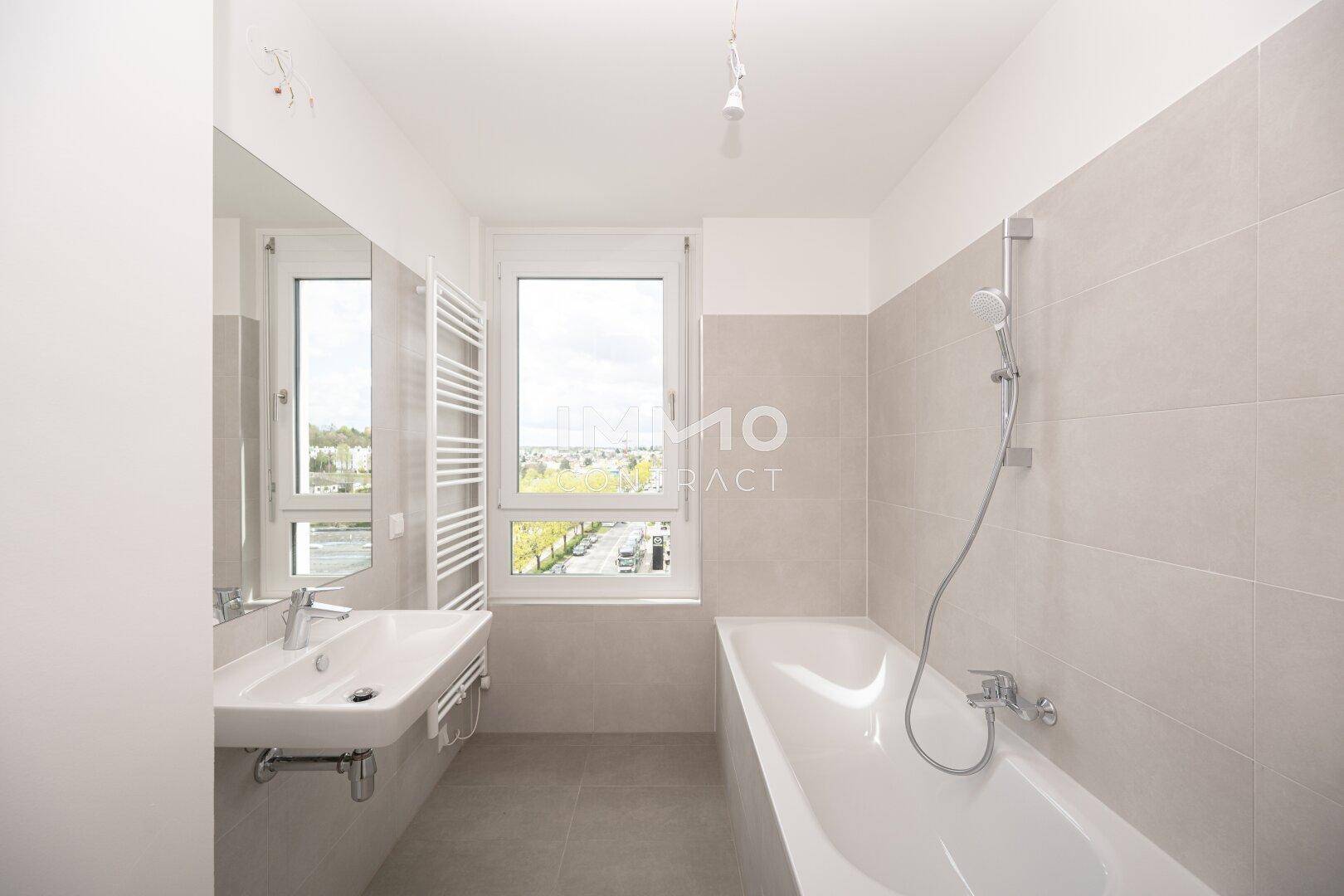 Modernes Badezimmer mit Badewanne, Einzelwaschbecken und beheiztem Handtuchhalter.