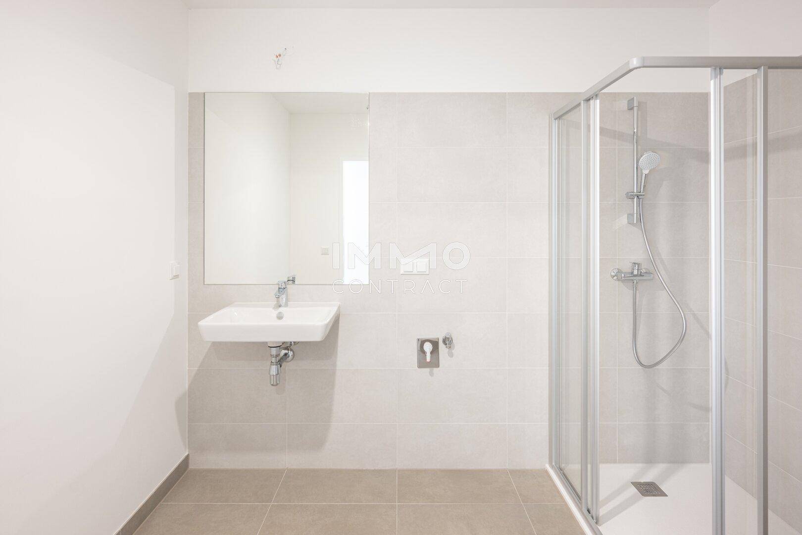 Modernes Badezimmer mit Duschkabine, Waschbecken und hellgrauen Fliesen an Wänden und Boden.