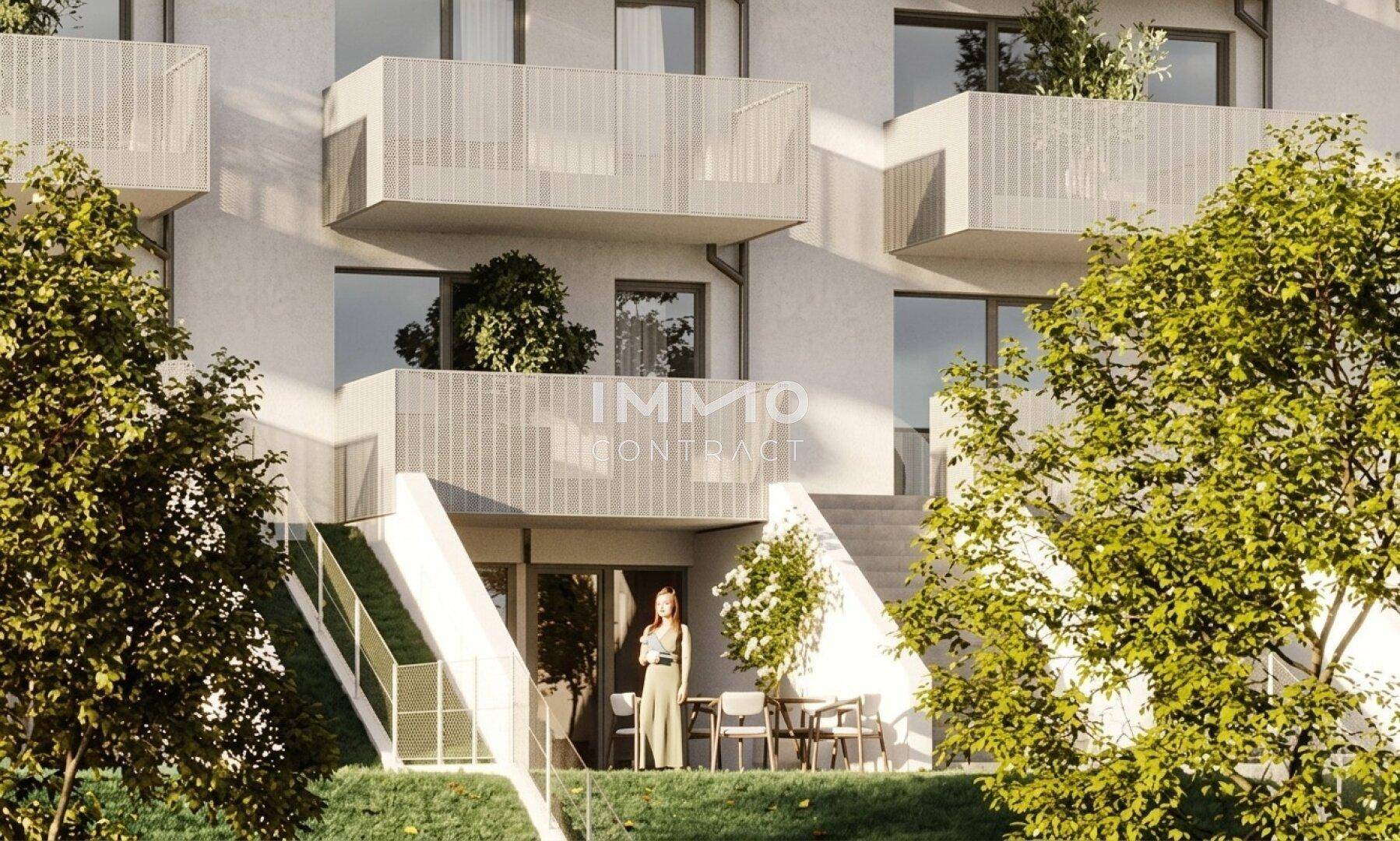 Moderne Wohnanlage mit Balkonen und einer einladenden Terrasse im Erdgeschoss, umgeben von Grün.