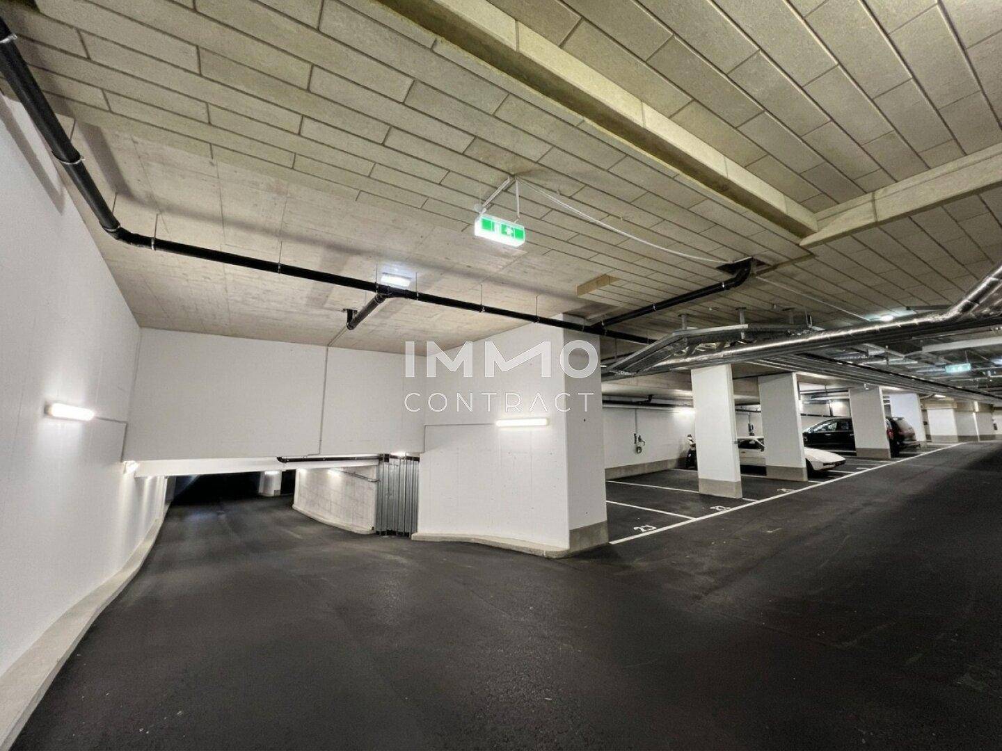 Tiefgarage mit markierten Stellplätzen, Beleuchtung und Zufahrtsrampe.