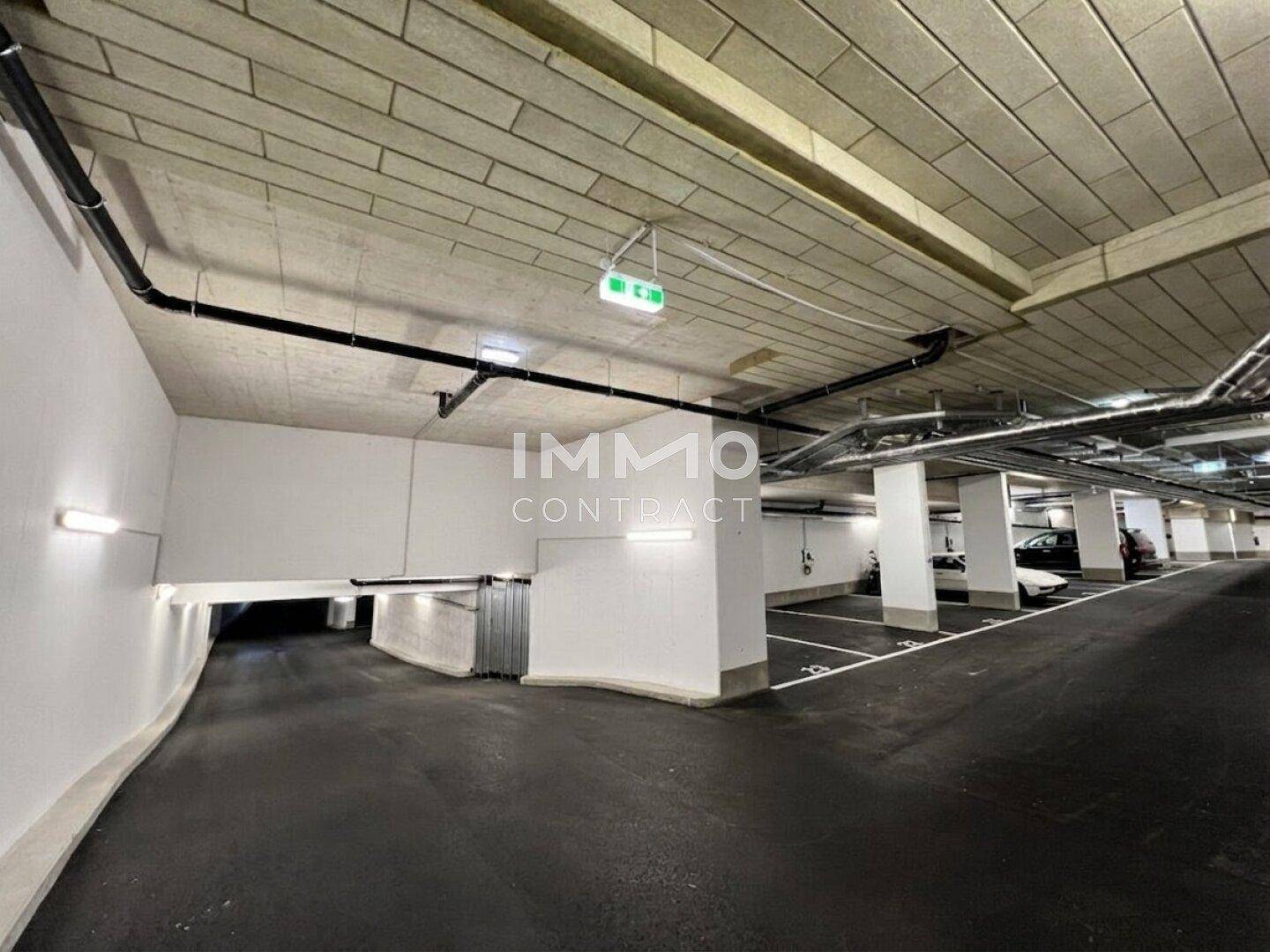 Weitläufige Tiefgarage mit vielen Parkplätzen, Zufahrt und moderner Beleuchtung.