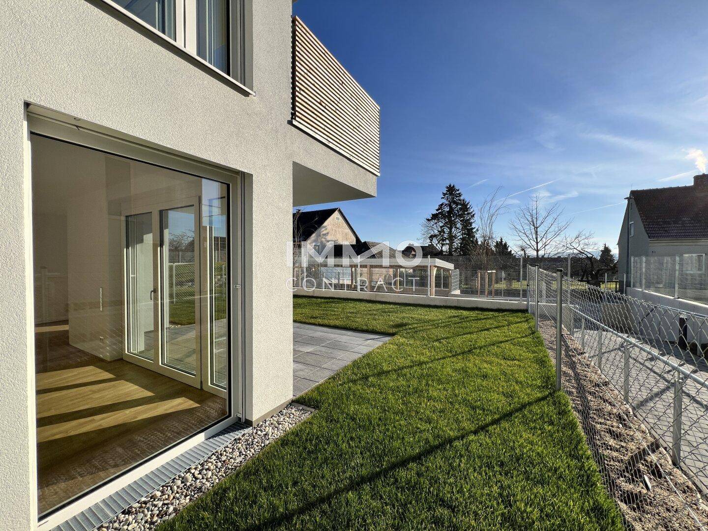 Große Fensterfront im Erdgeschoss mit Blick auf die grüne Rasenfläche und die umliegende Landschaft.