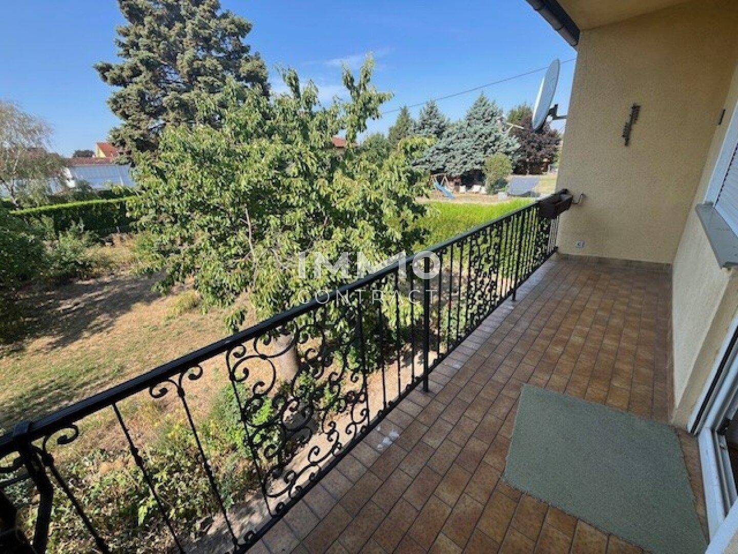 Balkon mit schmiedeeisernem Geländer und Blick auf den Garten und die grüne Umgebung.