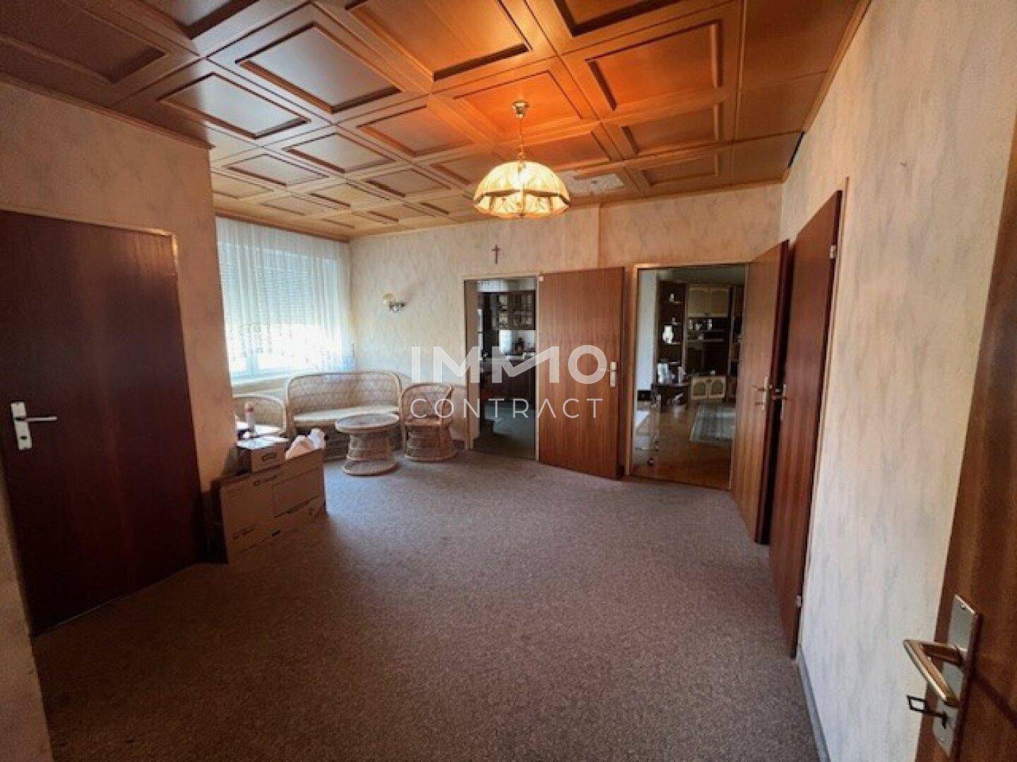 Wohnbereich mit Teppichboden, Holzdecke und mehreren Türen, die zu anderen Räumen führen.