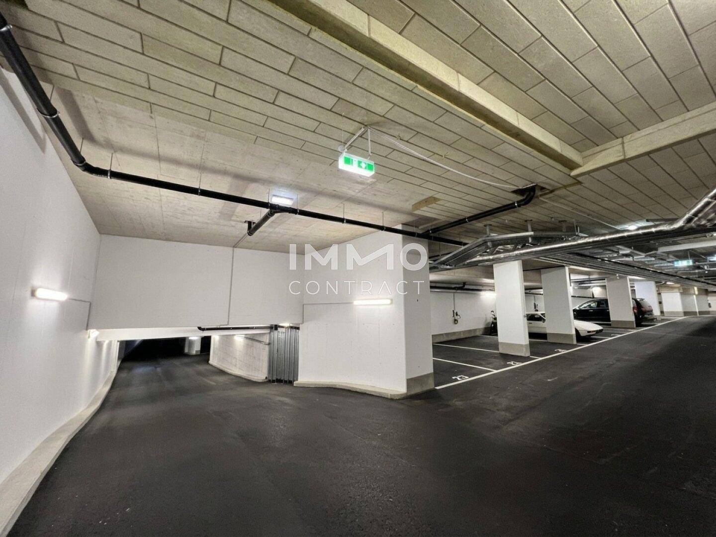 Moderne Tiefgarage mit markierten Stellplätzen, Betonpfeilern und einer Zufahrtsrampe.