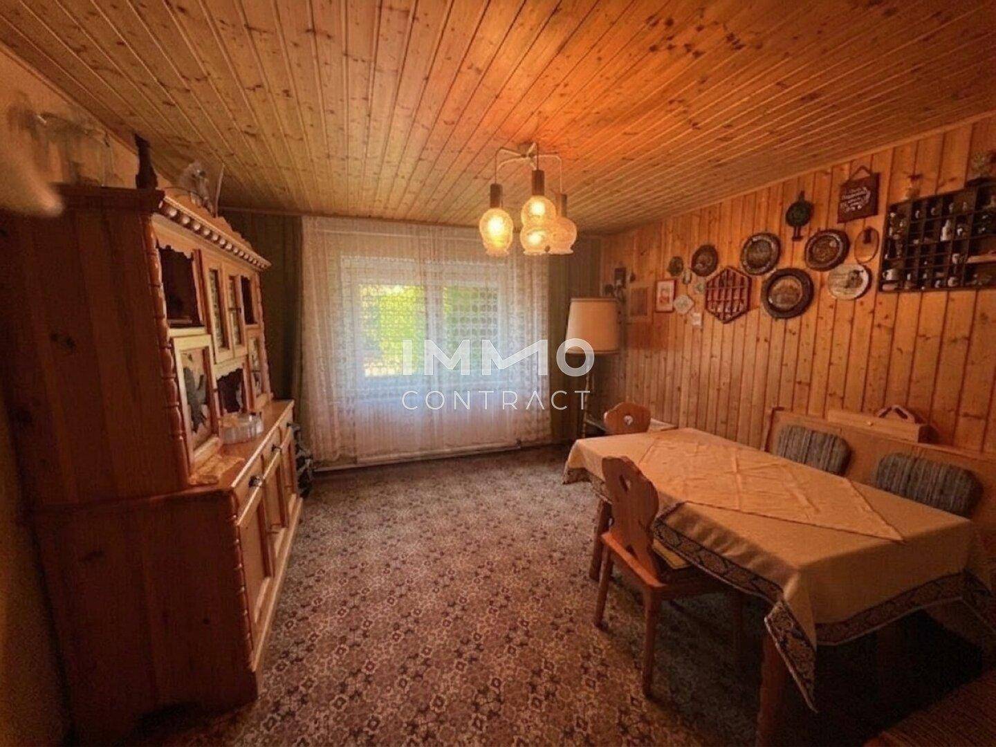 Esszimmer mit Holztäfelung, Teppichboden und einem traditionellen Holzschrank.