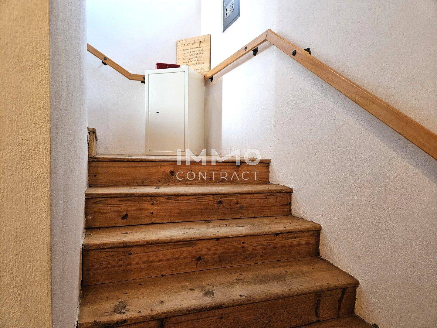 Holztreppe mit Handlauf führt in ein Obergeschoss, rustikal und funktional gestaltet.