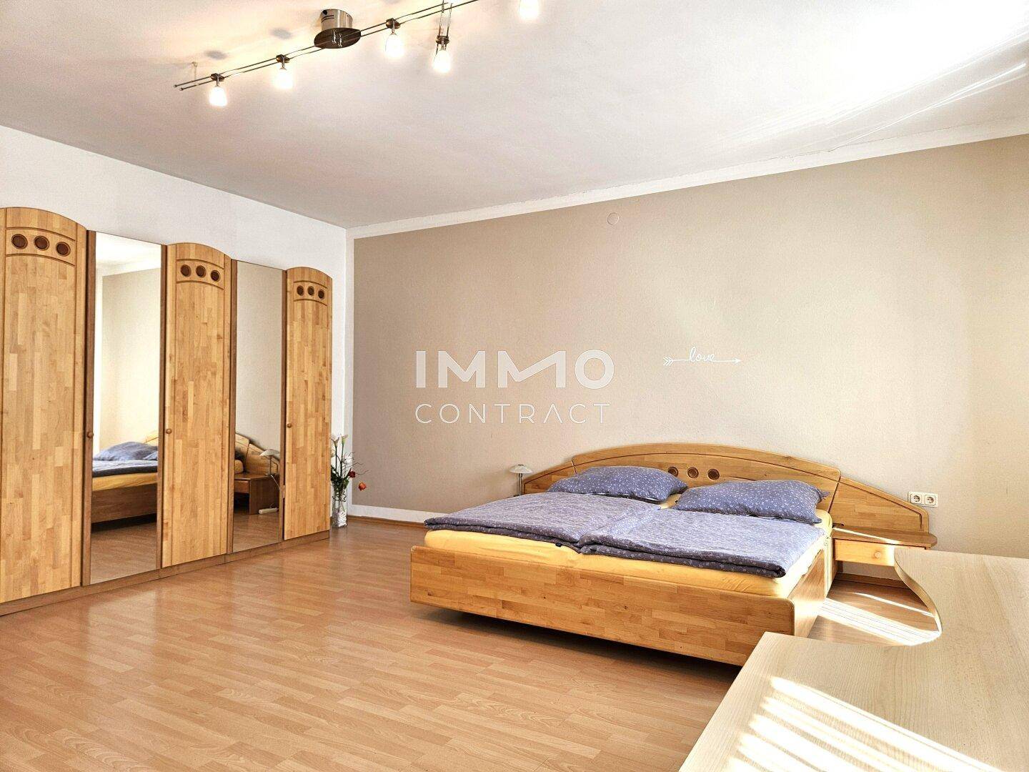 Schlafzimmer mit großem Kleiderschrank, Doppelbett und hellem Laminatboden, funktional und geräumig.