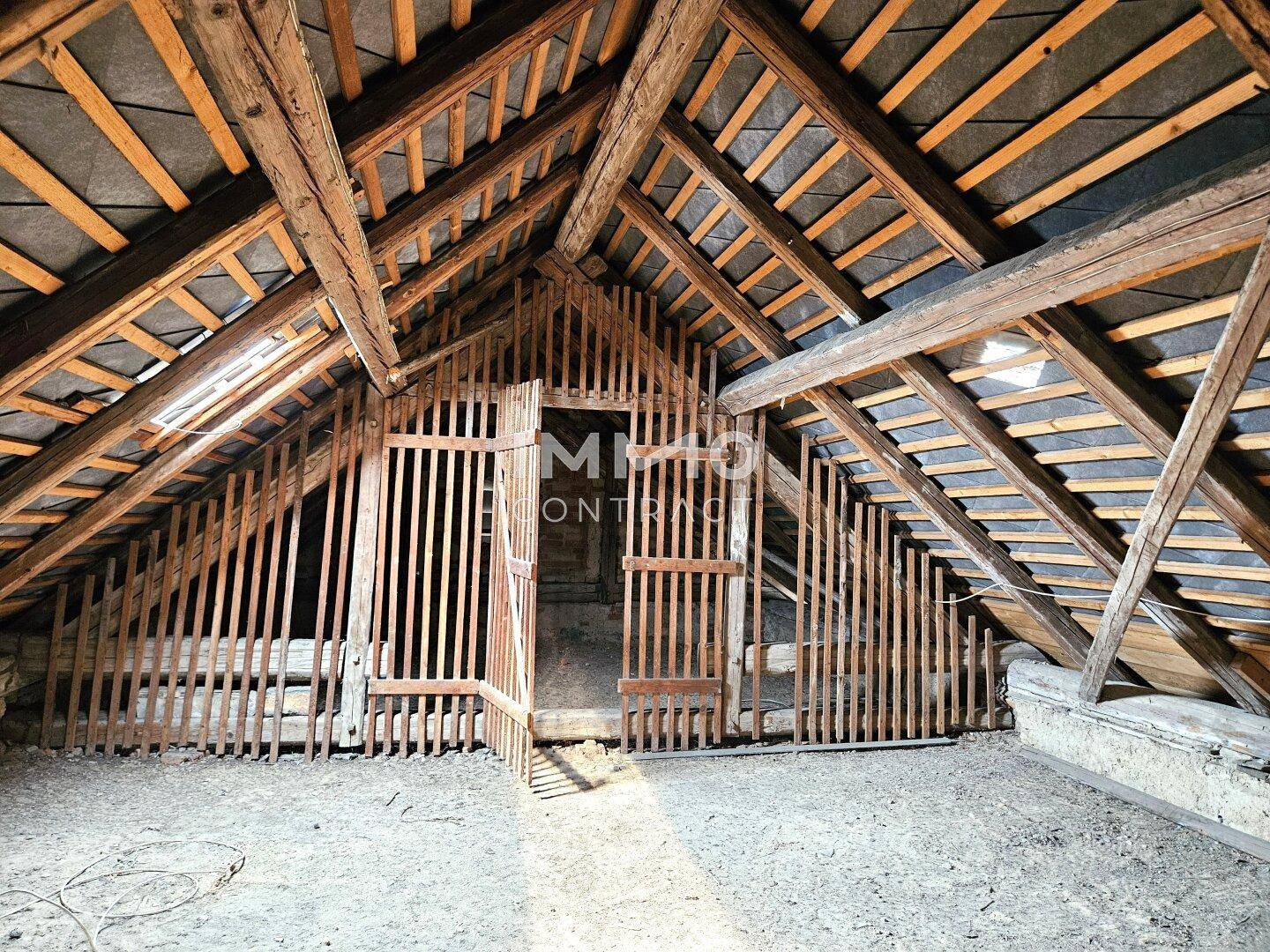 Dachboden mit freiliegenden Holzdachstühlen und einer hölzernen Lattenabtrennung, bietet viel Stauraum.