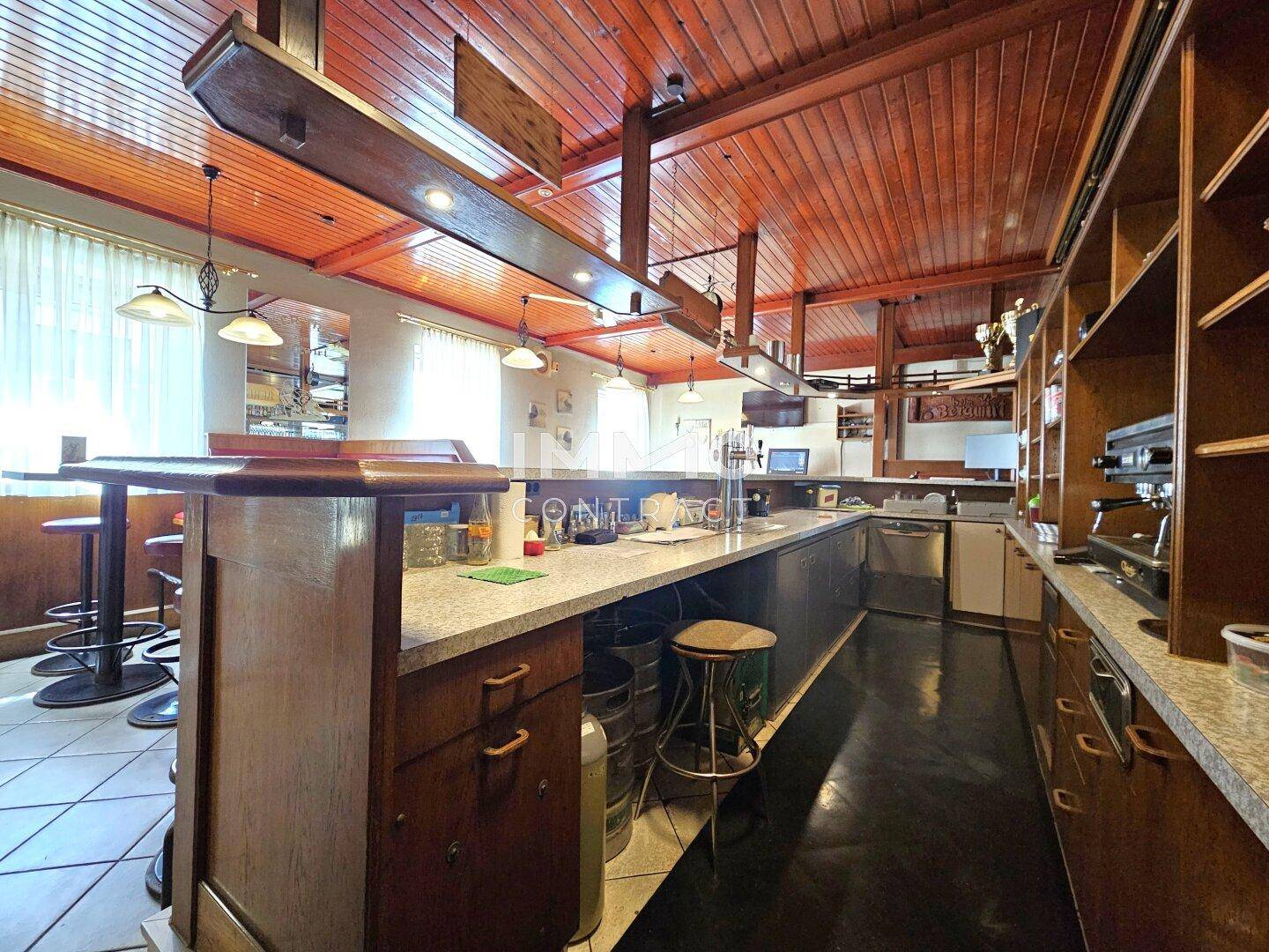 Lange Theke einer Bar mit Granit-Arbeitsplatte, Holzverkleidung und integrierten Geräten, bereit für den Betrieb.