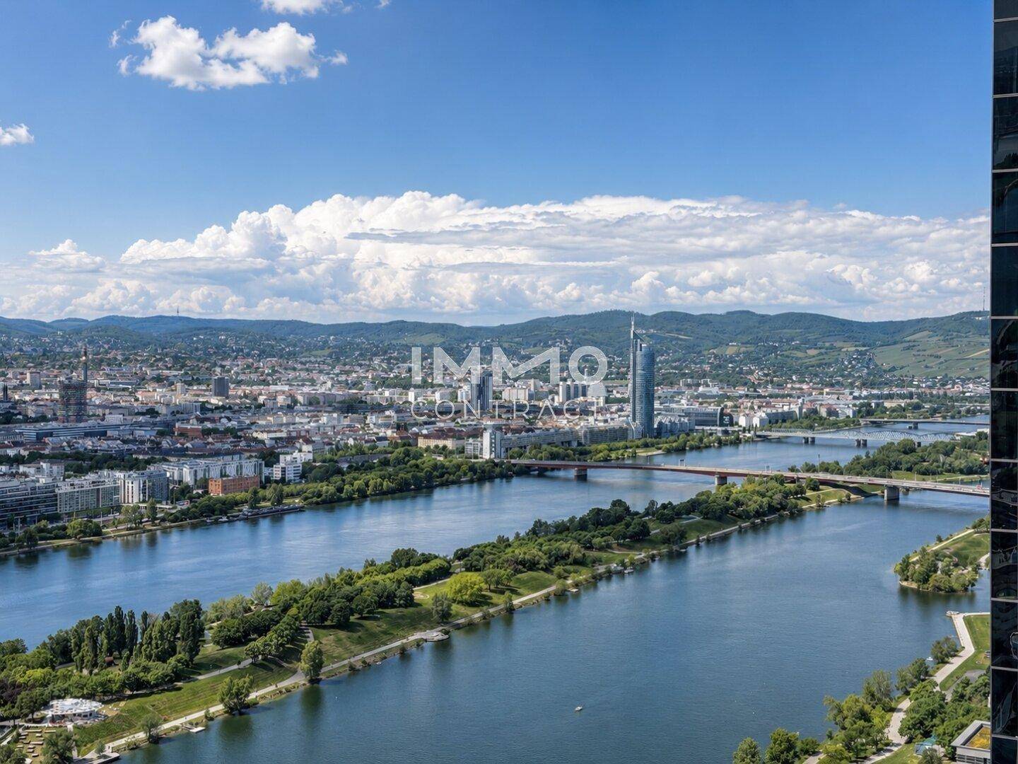 Panoramablick über die Stadt, den Fluss und die umliegende Landschaft unter blauem Himmel.