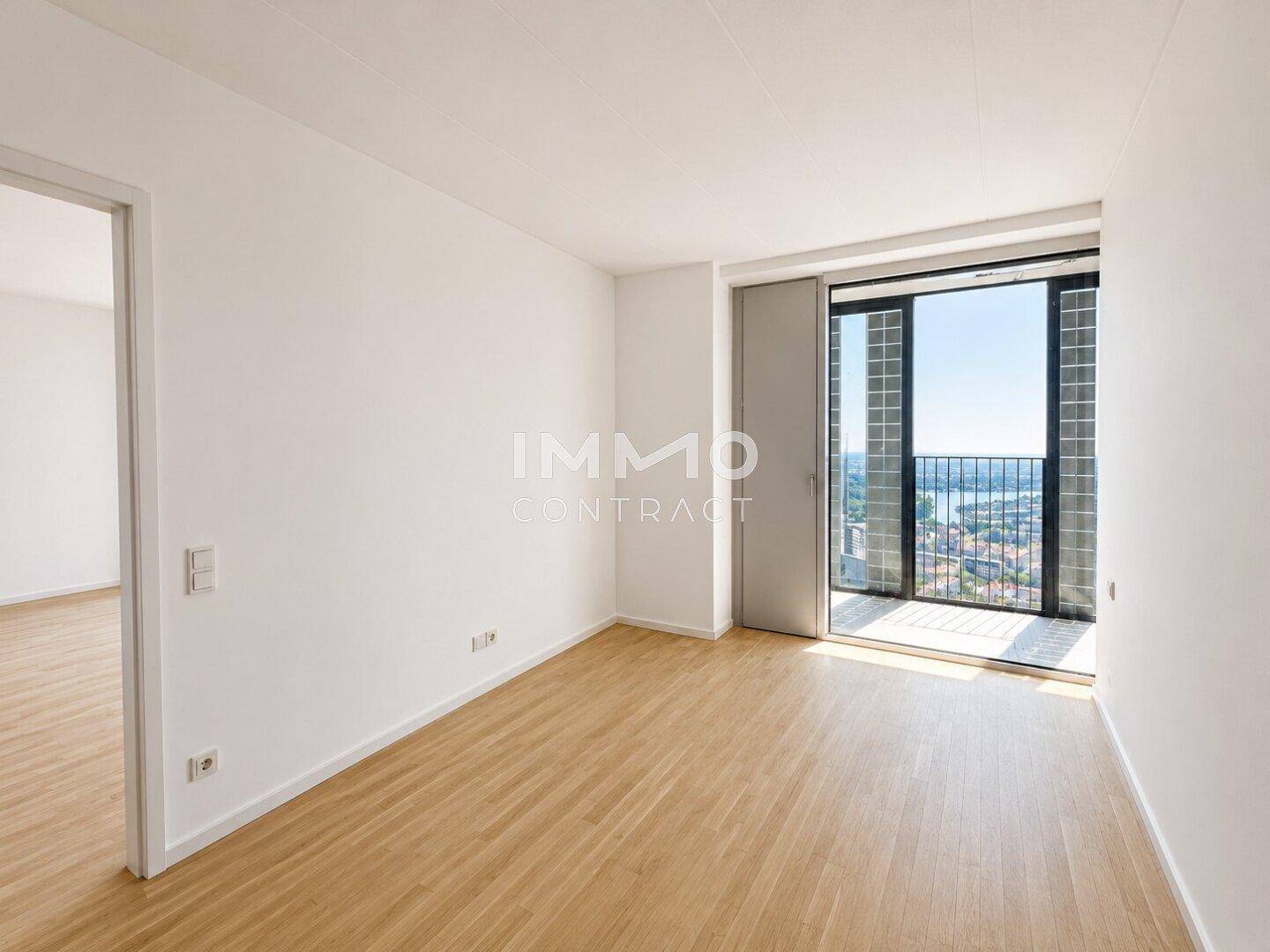 Helles Schlafzimmer mit Holzboden und Zugang zu einem Balkon mit weitem Stadtblick.