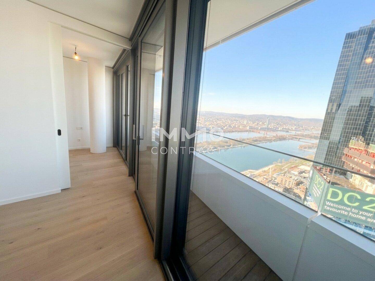 Balkon mit Glasbrüstung und weitem Blick über die Stadt und den Fluss.