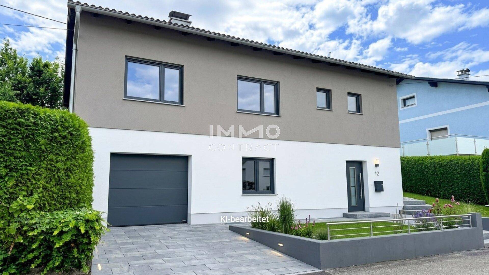 Modernes Einfamilienhaus mit zweifarbiger Fassade, integrierter Garage und gepflegtem Vorgarten.