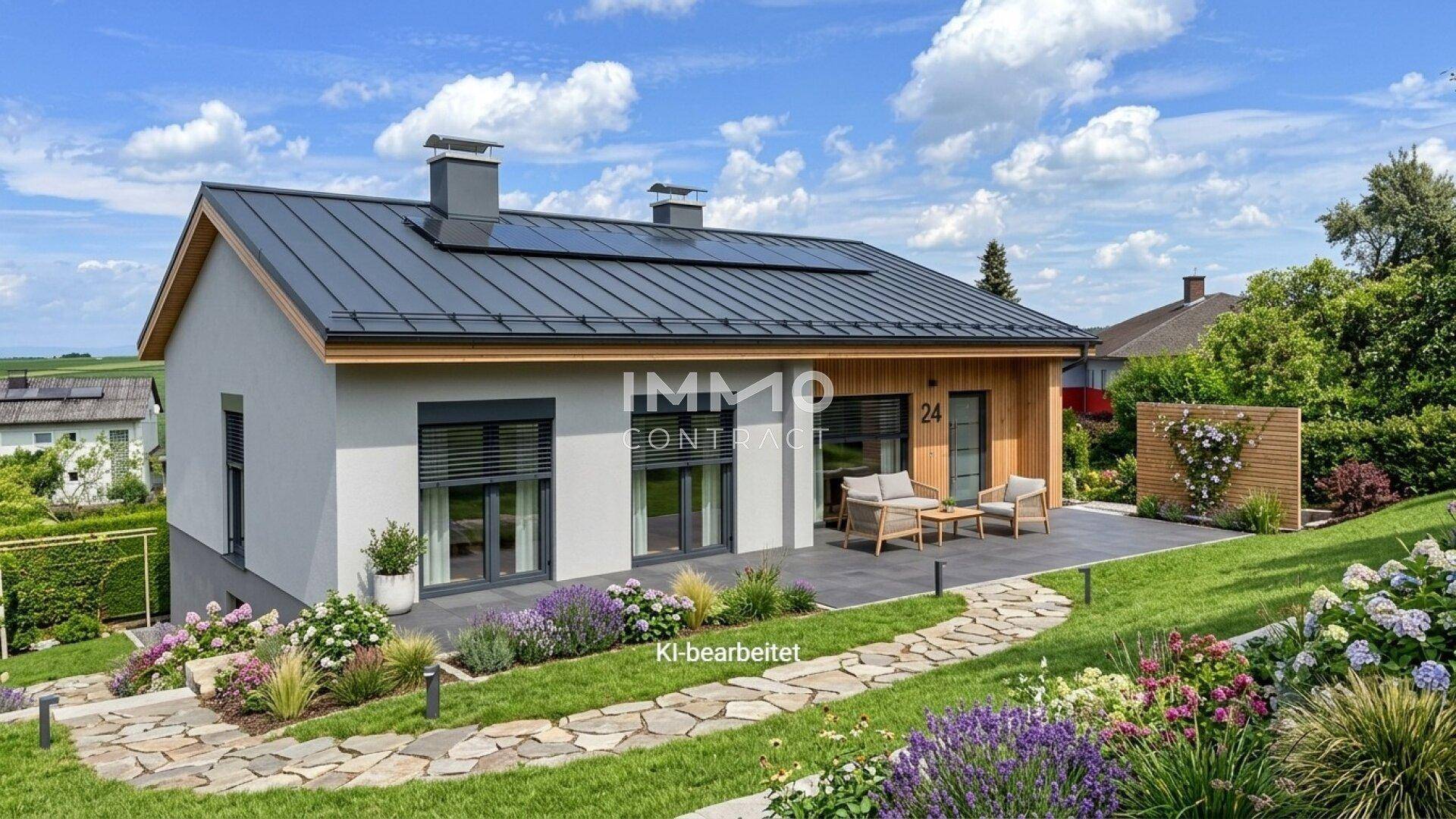 Modernes Haus mit großer Terrasse, gepflegtem Garten und Photovoltaikanlage auf dem Dach.