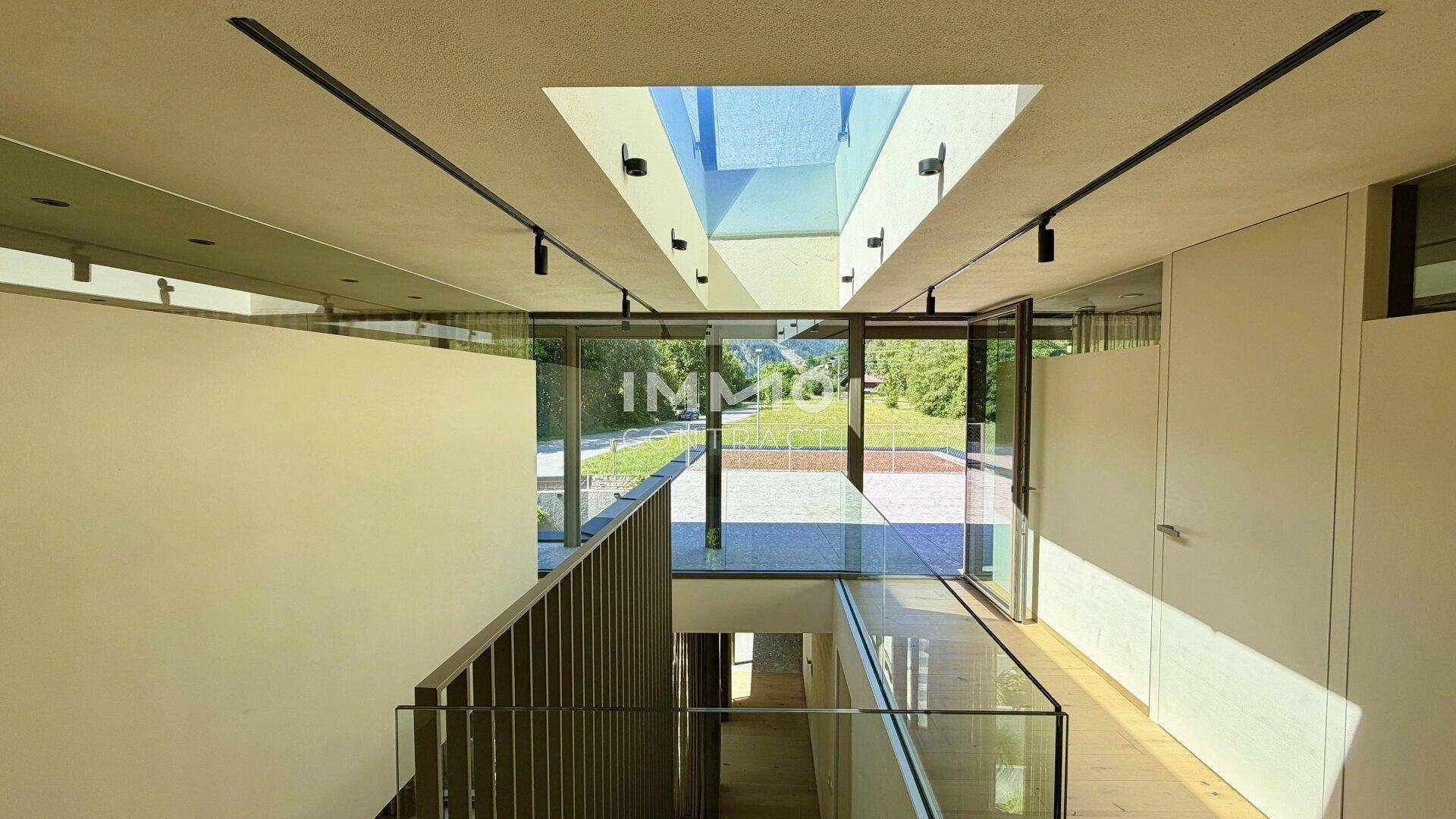 Heller Treppenaufgang mit Glasgeländer, großzügigen Fenstern und einem Oberlicht für viel Tageslicht.