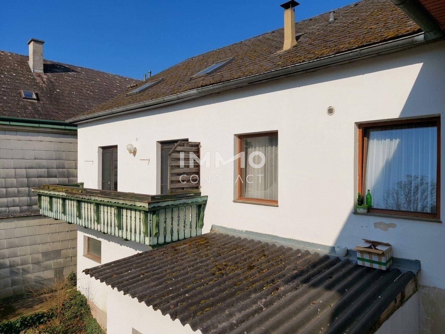 Alter Balkon mit Holzgeländer an der Fassade eines traditionellen Gebäudes.