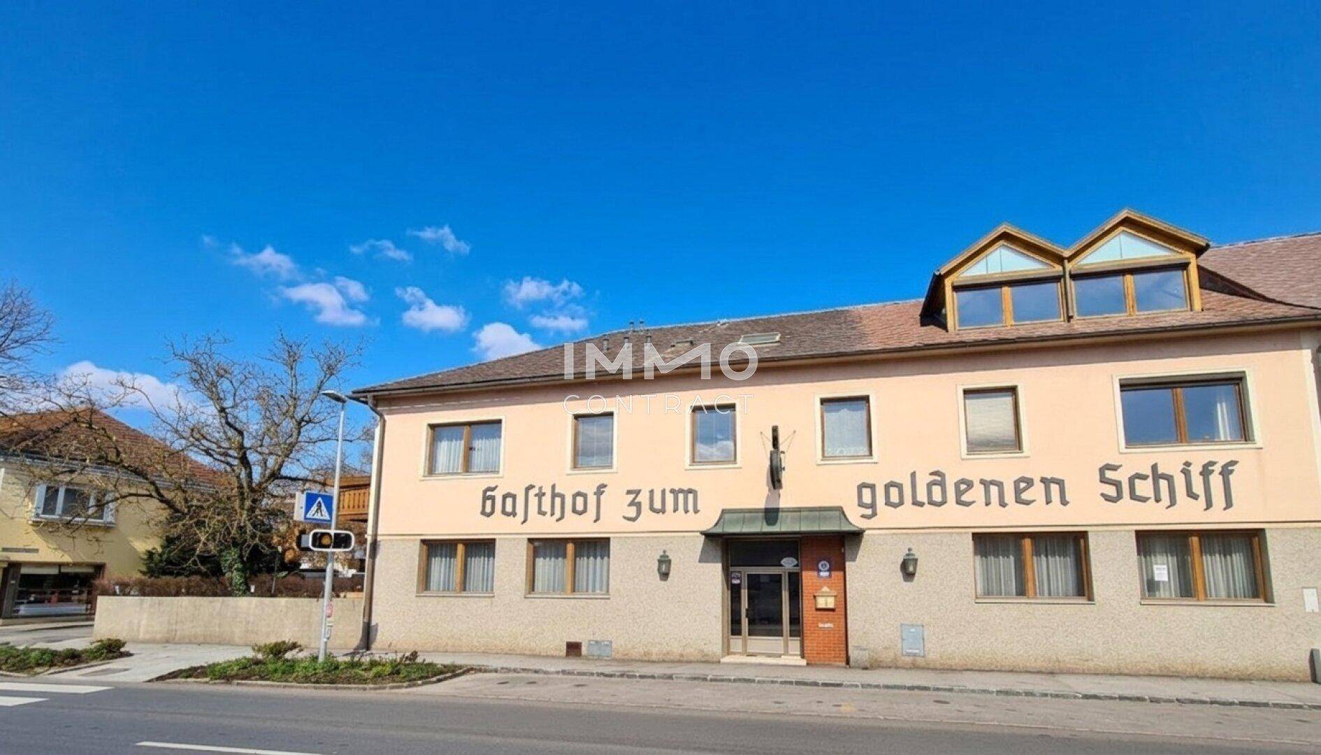 Historisches Gebäude mit Gasthof-Beschriftung und Mansarddach unter blauem Himmel.