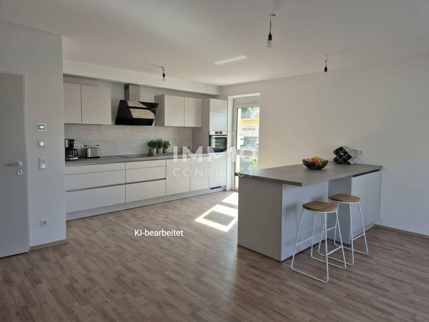 Moderne offene Küche mit Kücheninsel, hellgrauen Schränken und Laminatboden in einem Wohnraum.