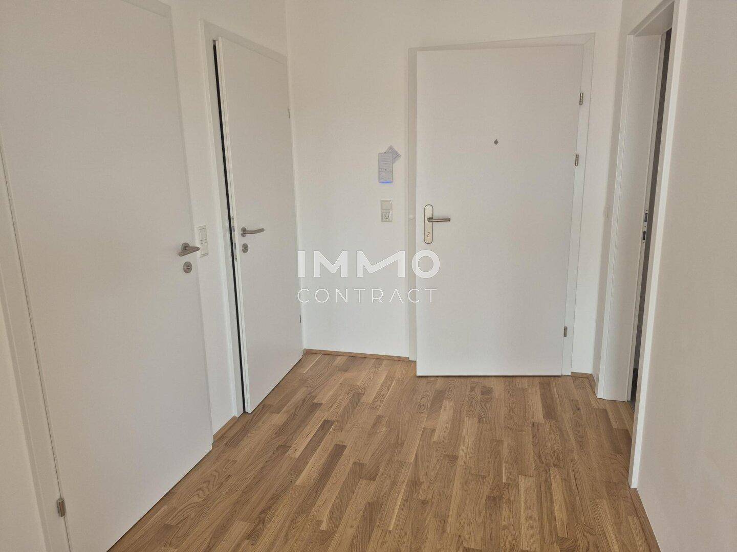 Heller Flur mit Holzboden und mehreren weißen Türen, der verschiedene Räume verbindet.