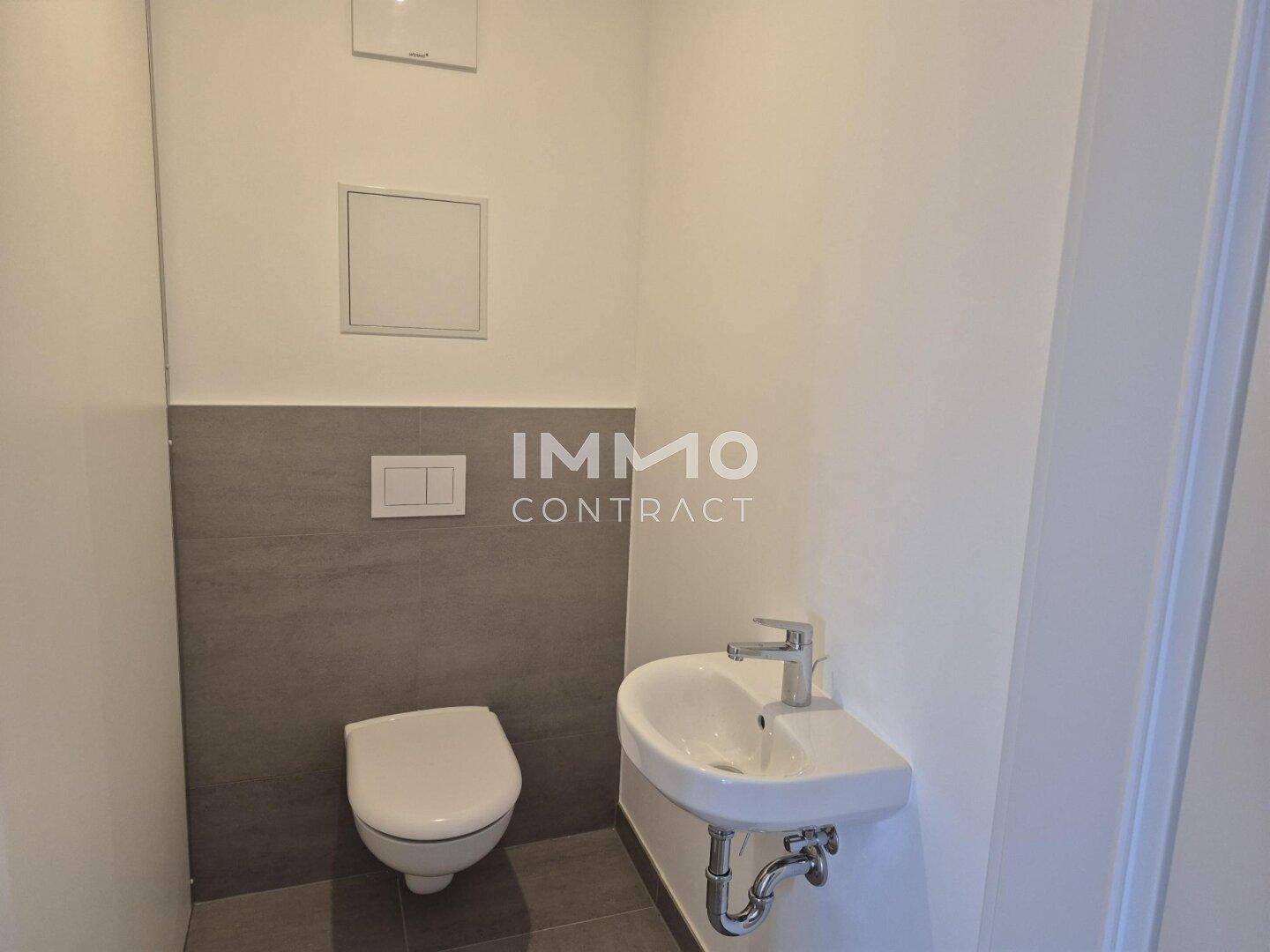 Kleines Gäste-WC mit wandhängender Toilette und kompaktem Waschbecken, in Grau und Weiß gehalten.