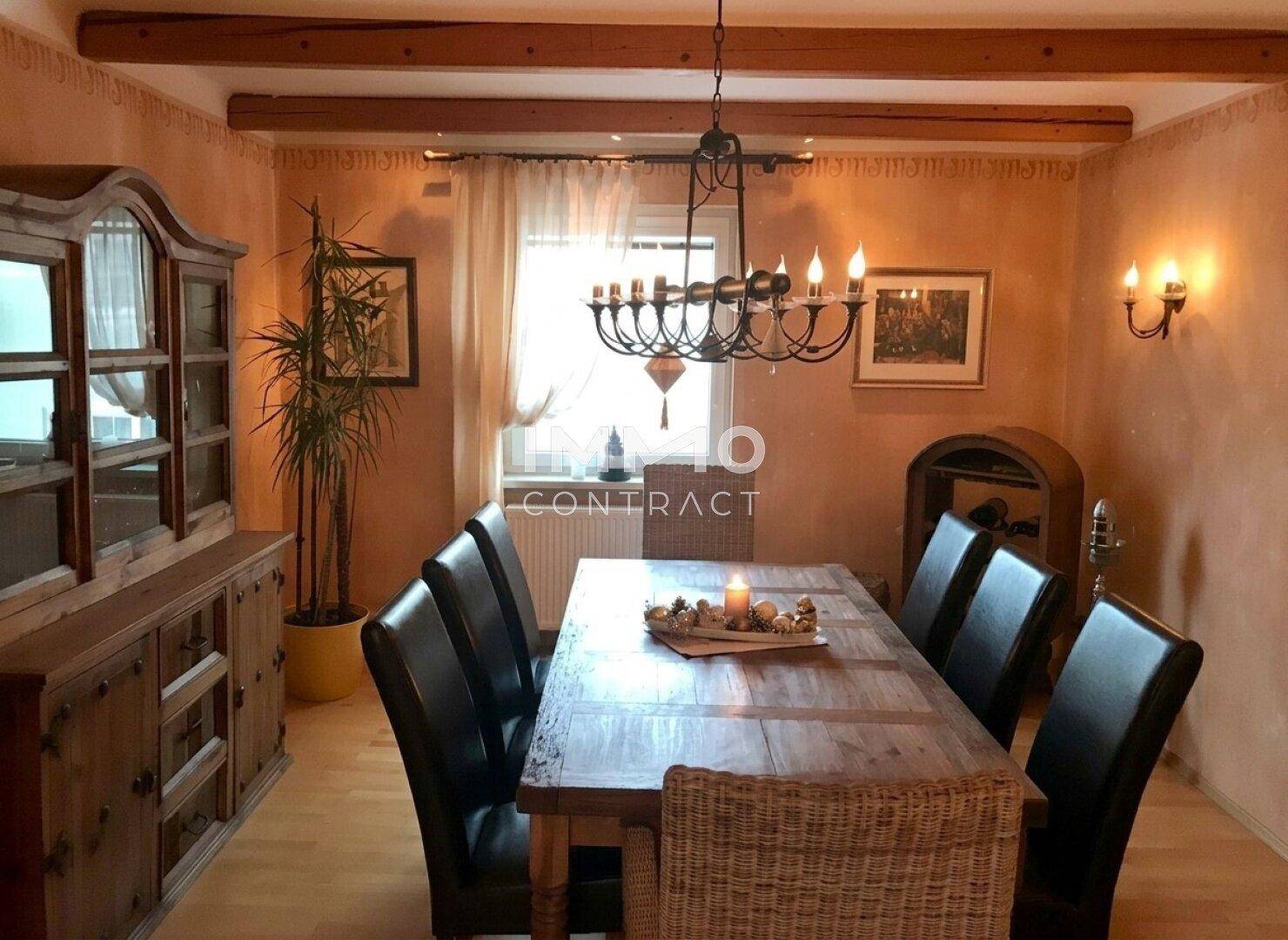 Gemütliches Esszimmer mit Holztisch, dunklen Stühlen und sichtbaren Deckenbalken.