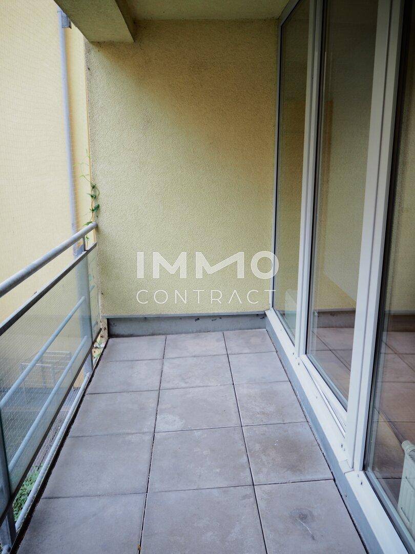 Heller Balkon mit Fliesenboden und Glasgeländer, bietet einen angenehmen Außenbereich.