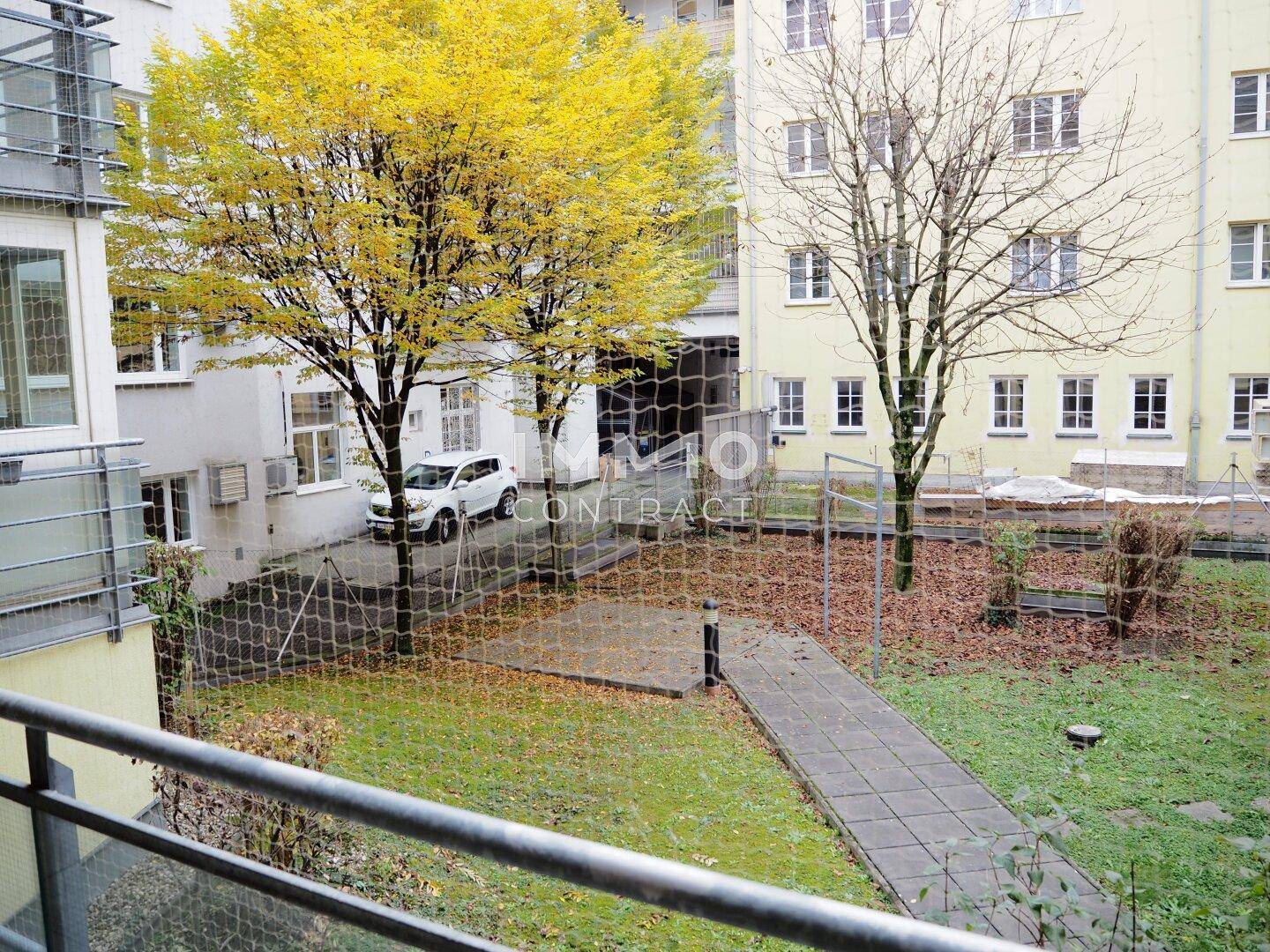 Blick auf den begrünten Innenhof mit Bäumen und einem gepflasterten Weg.