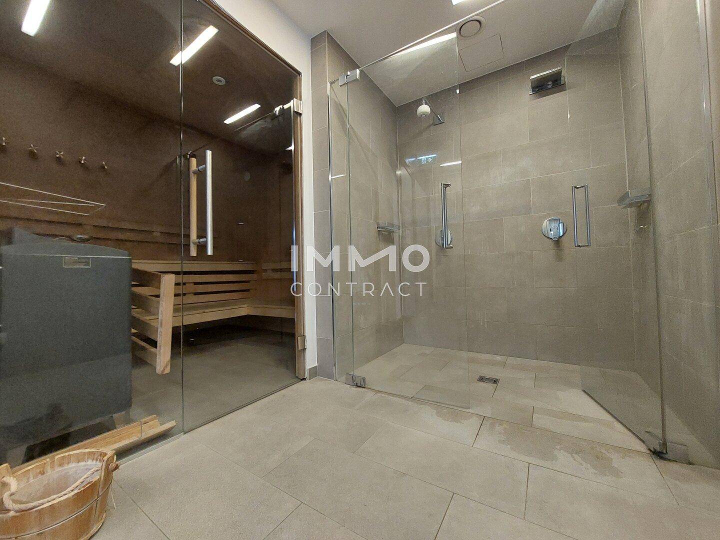 Duschbereich mit Glasabtrennung direkt neben dem Eingang zur Sauna.