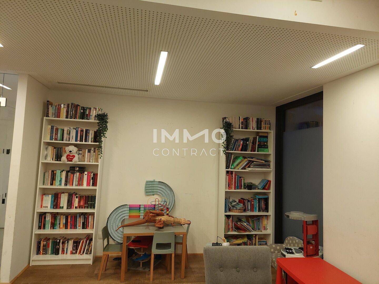 Gemütlicher Wohnbereich mit zwei großen Bücherregalen, kleinem Tisch und Holzboden.
