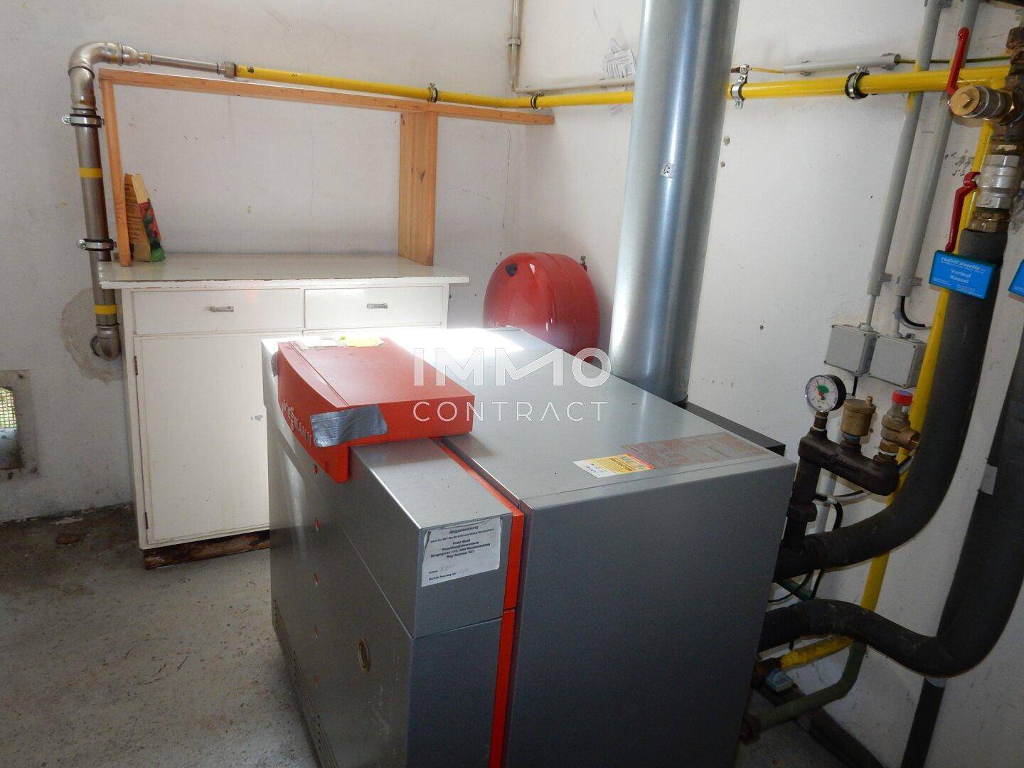 Nahaufnahme einer modernen Heizungsanlage mit Rohren und Anschlüssen in einem Technikraum.