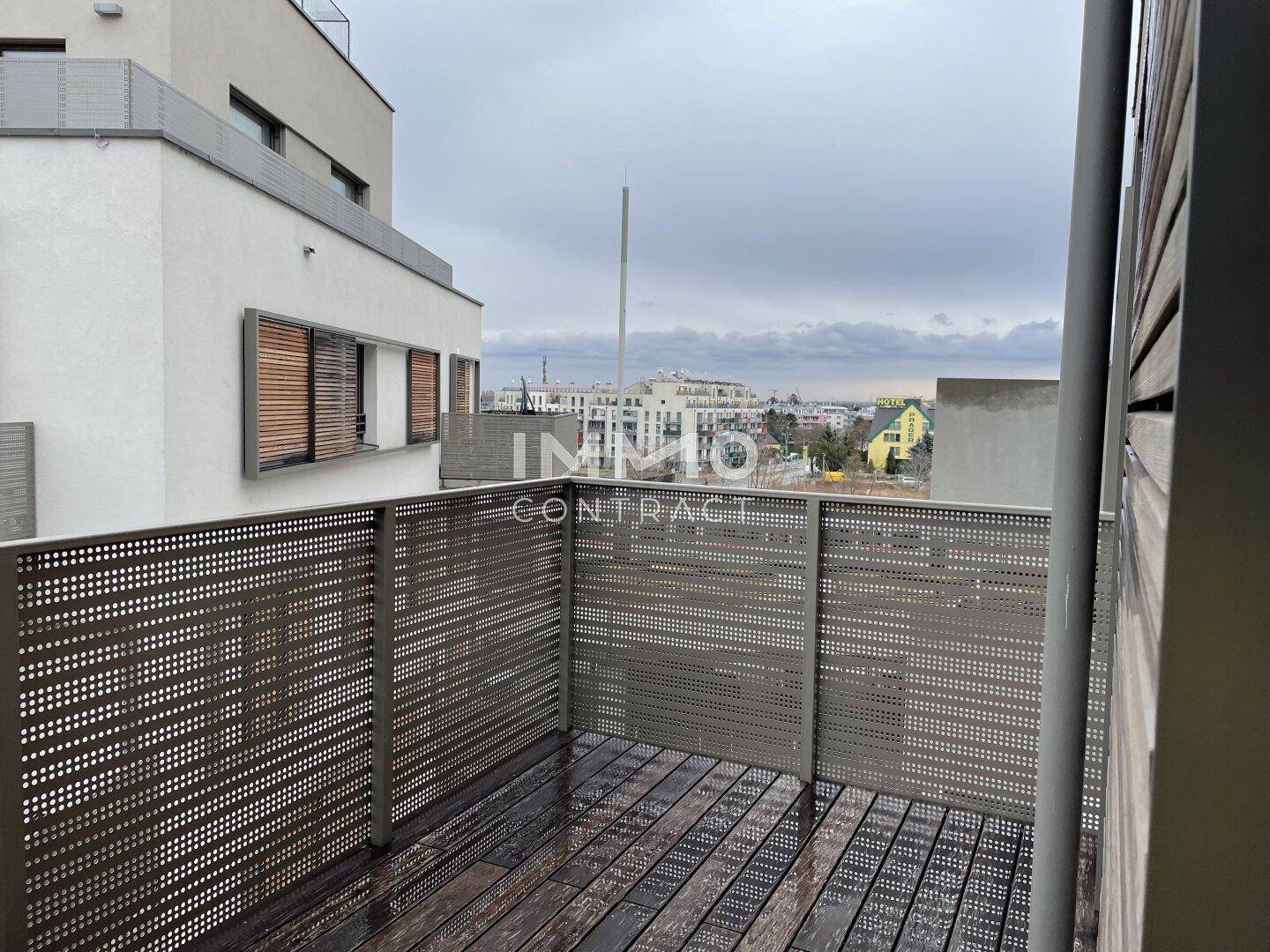Balkon mit Holzboden und Metallgeländer bietet einen weiten Blick über die Stadt.