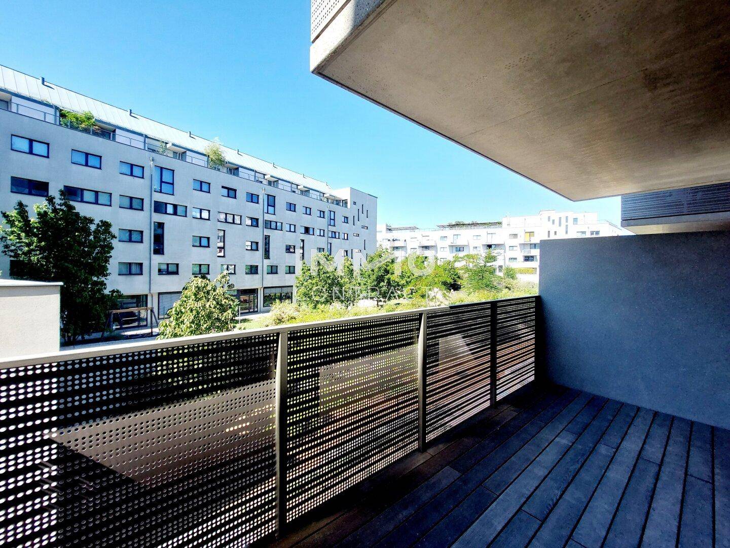 Heller Balkon mit Holzbelag und weitem Blick auf die umliegende moderne Architektur.