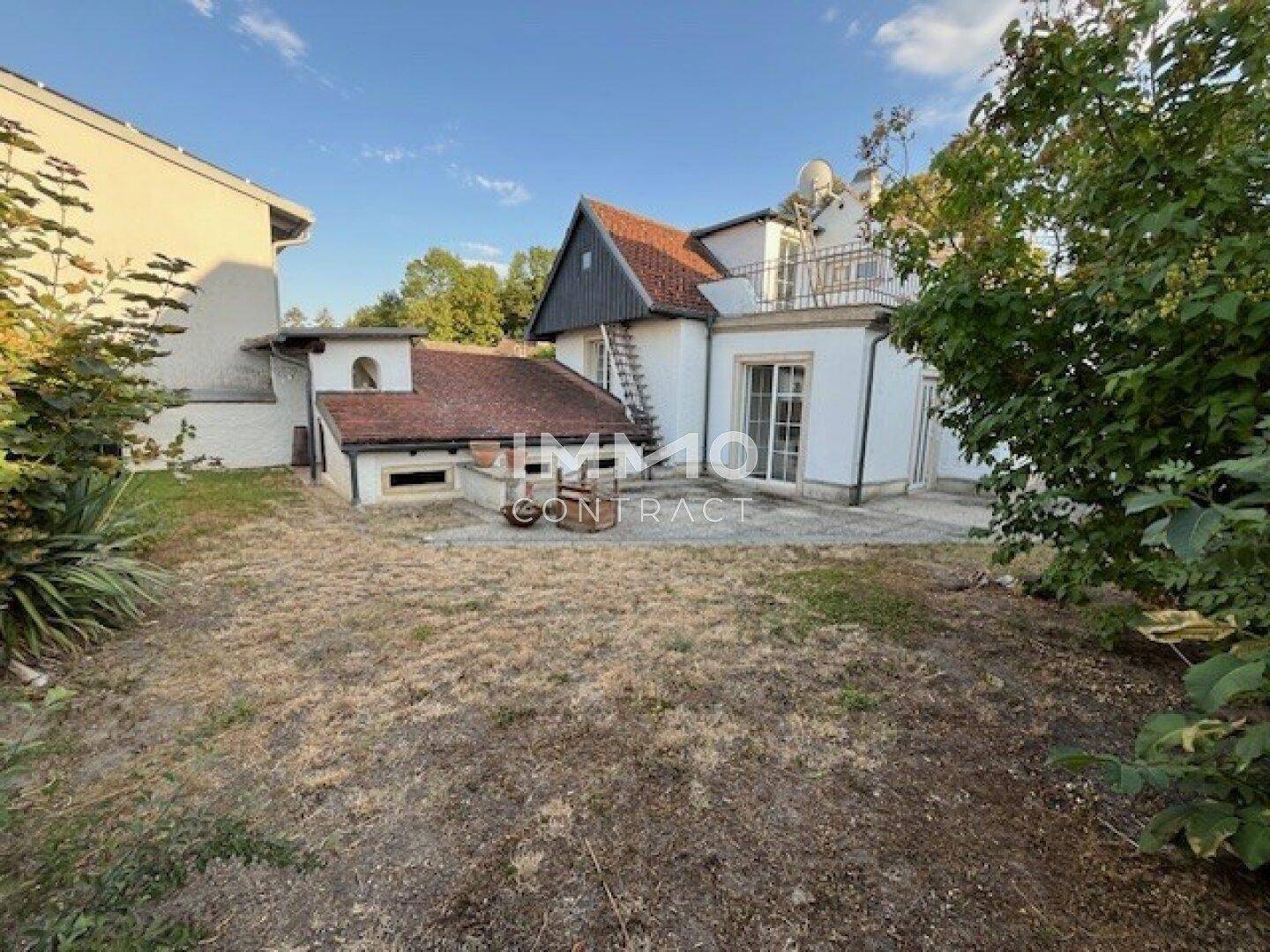 Großer Gartenbereich mit Rasenfläche und einer Terrasse vor dem Haus.