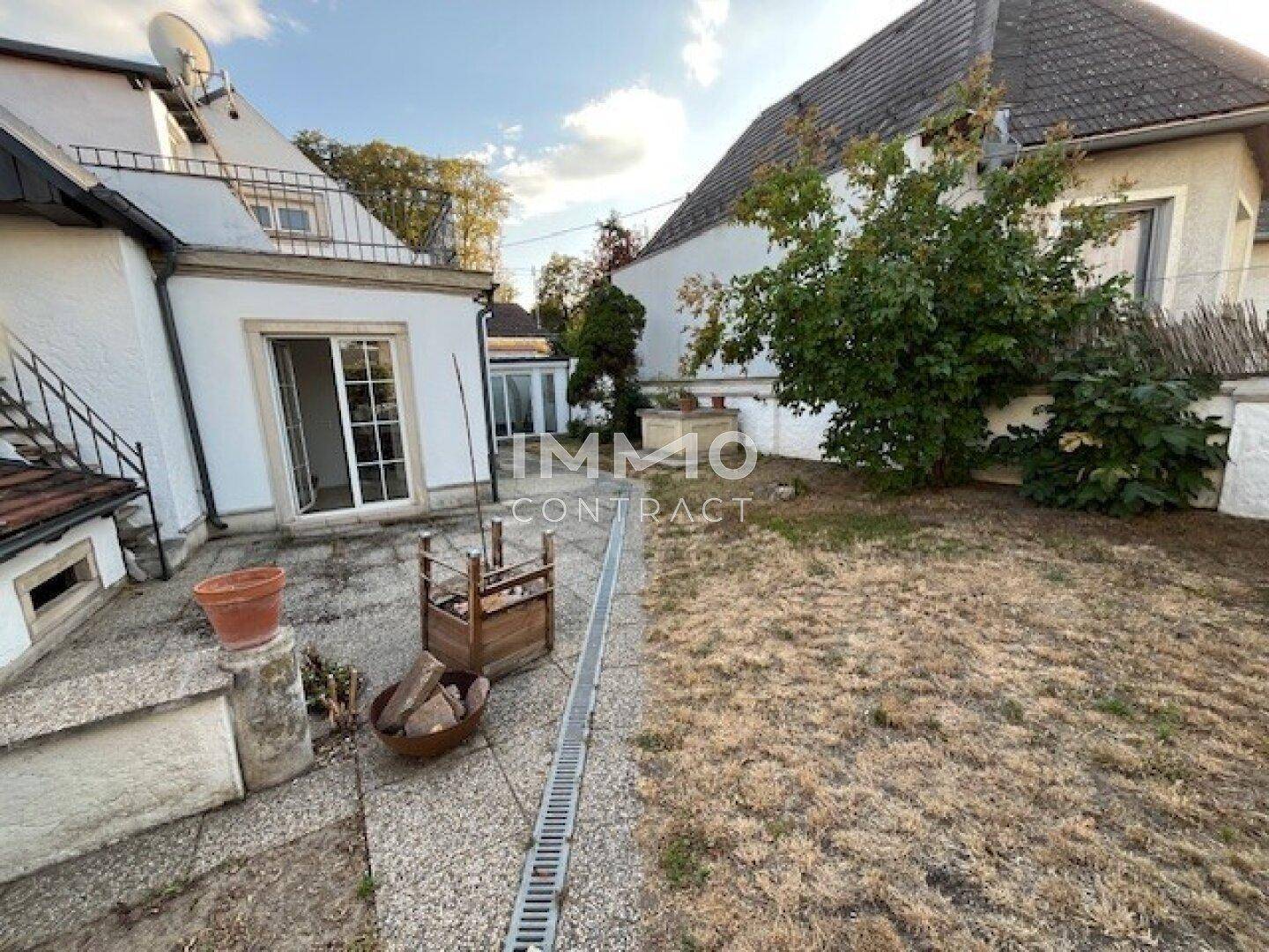 Sonniger Garten mit gepflasterter Terrasse und Rasenfläche, ideal für Entspannung.