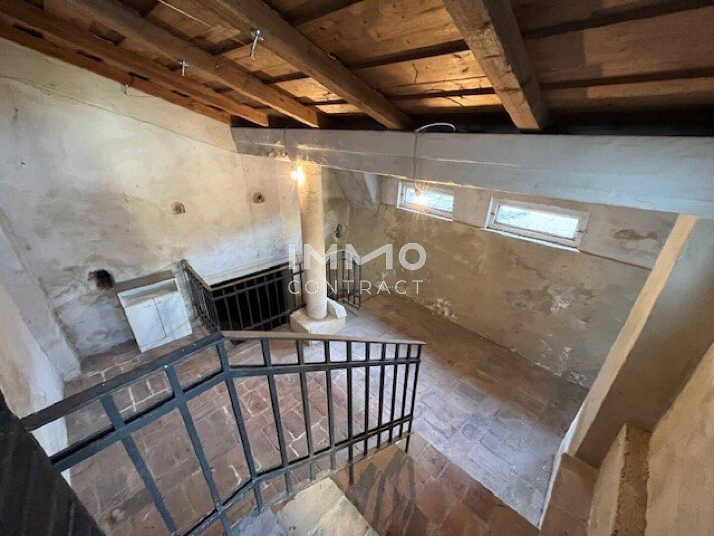 Unausgebauter Kellerraum mit freiliegenden Holzbalken und Steintreppe.