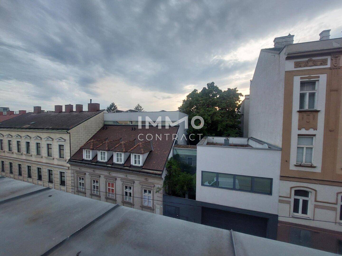 Blick über die Dächer der Stadt mit angrenzenden Gebäuden und etwas Grün.