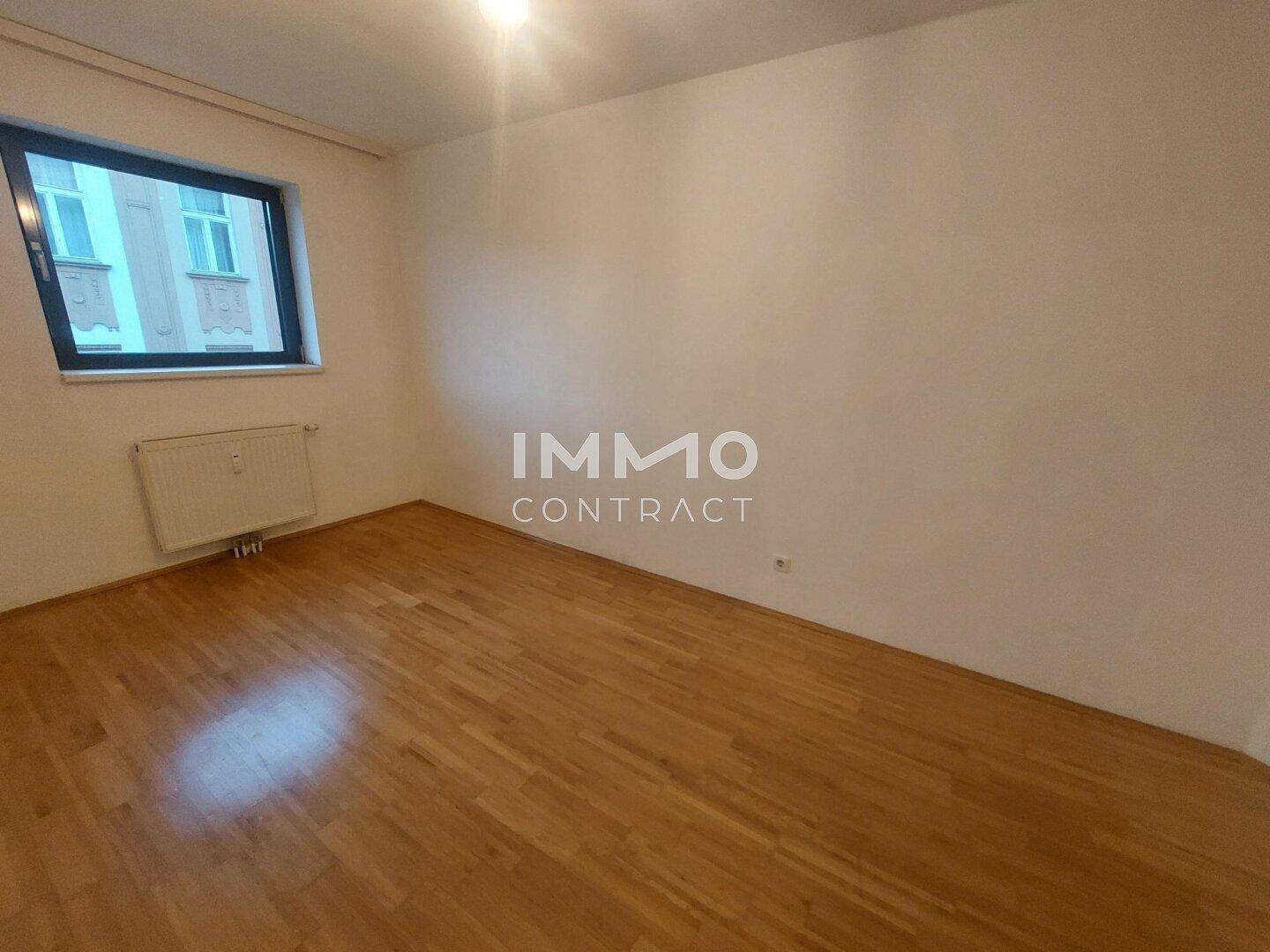Geräumiges Zimmer mit Parkettboden und einem Fenster, das für natürliche Belichtung sorgt.