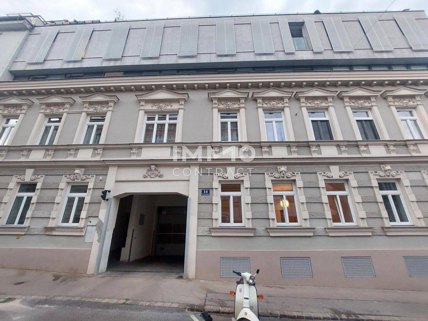 Historische Fassade eines Wohngebäudes mit vielen Fenstern und einem Eingangsbereich.