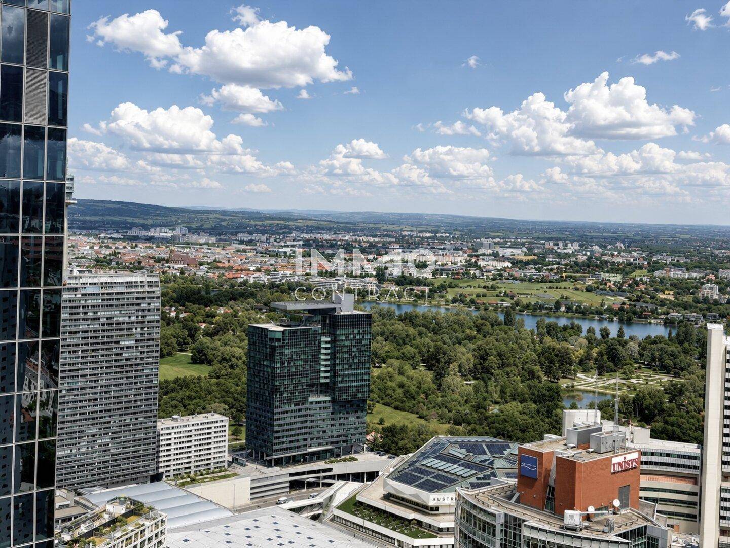 Weitläufiger Blick auf die moderne Stadtarchitektur, den Fluss und die umliegende grüne Landschaft.