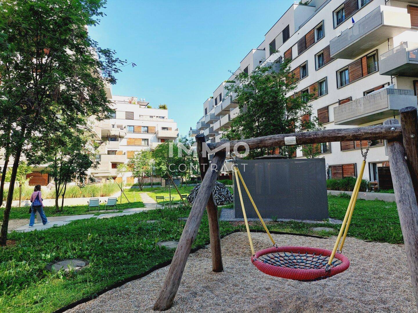 Kinderspielplatz mit Schaukel und Grünflächen in einer modernen Wohnsiedlung.
