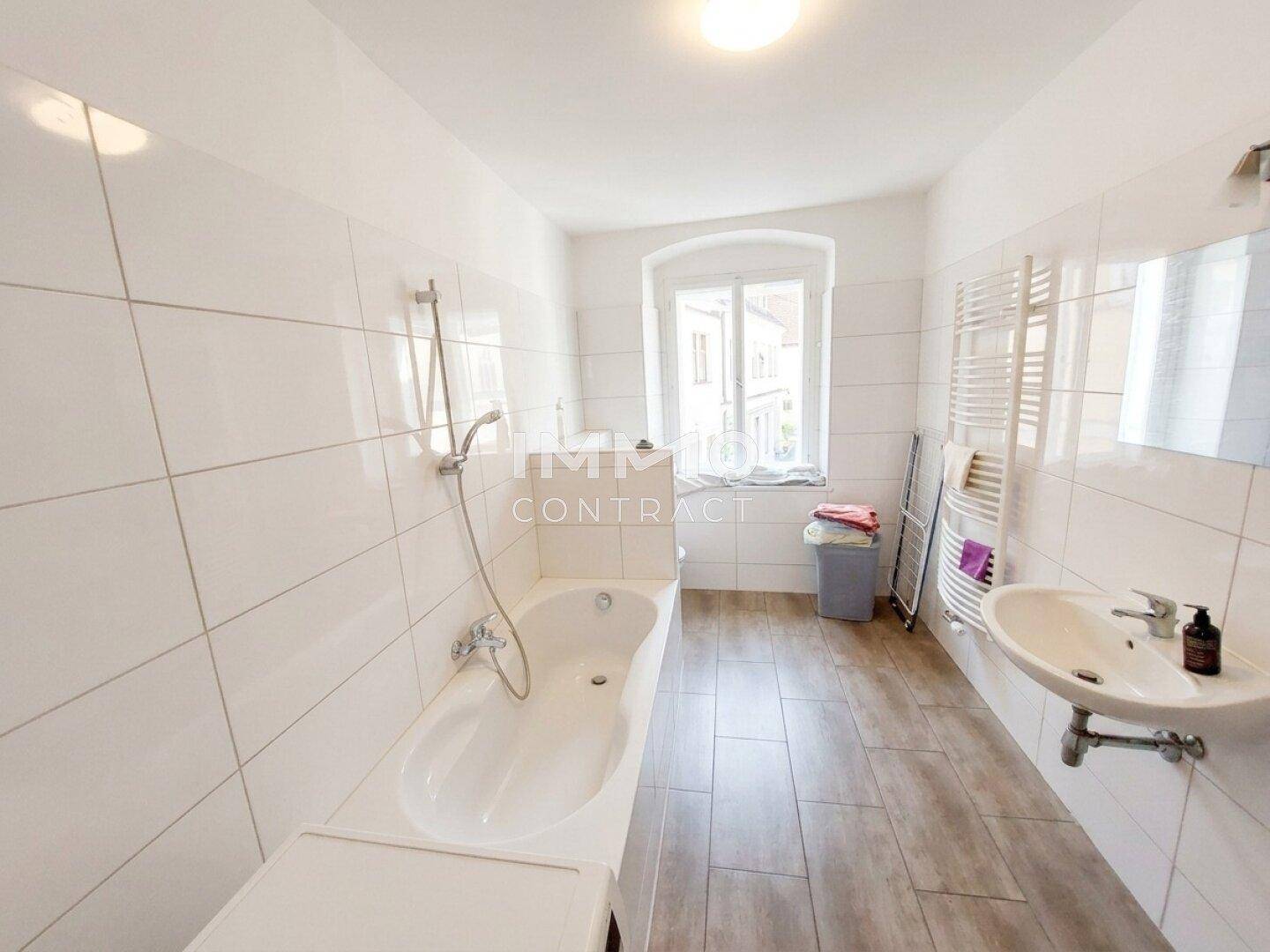Helles Badezimmer mit Badewanne, Waschbecken und beheiztem Handtuchhalter.