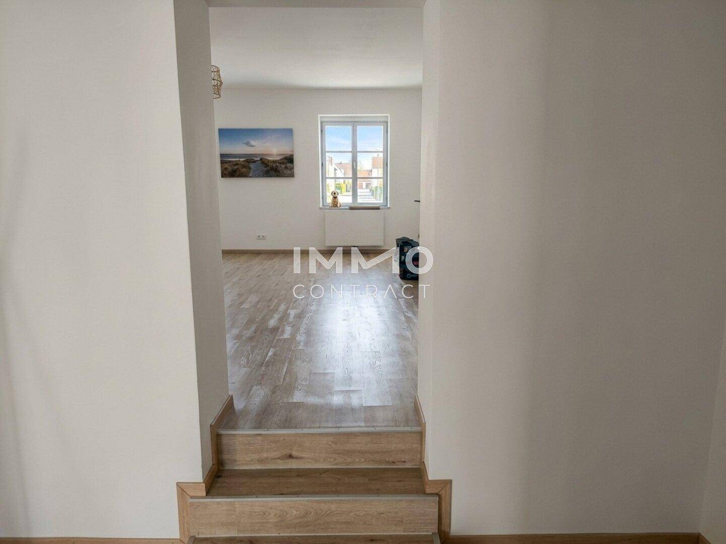 Heller Flur mit Laminatboden und Treppe, die zu einem oberen Bereich führt.