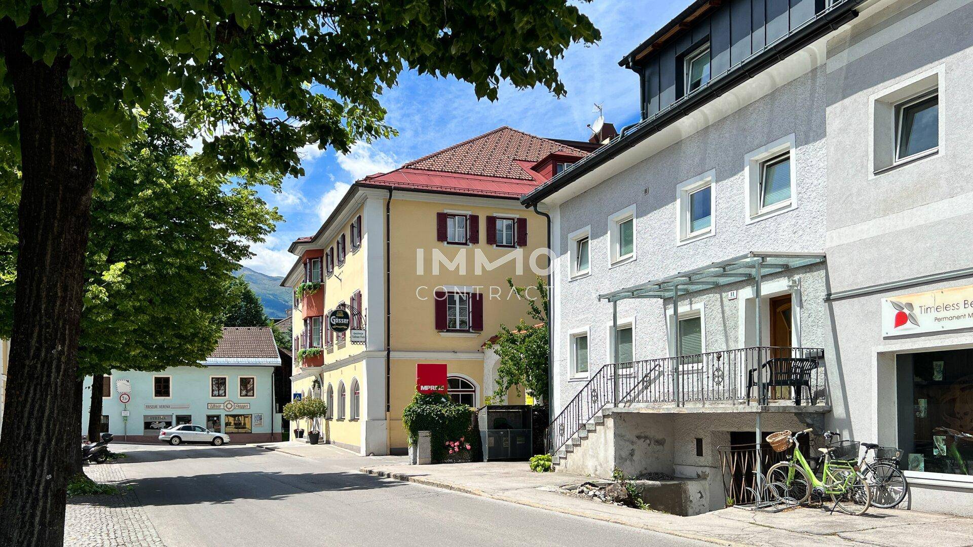 Blick auf eine belebte Straße mit verschiedenen Gebäuden und grüner Umgebung.