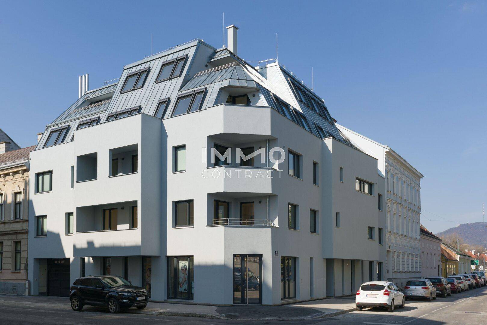 Modernes Wohngebäude mit markanter Dachkonstruktion und großen Fenstern an einer Straßenecke.