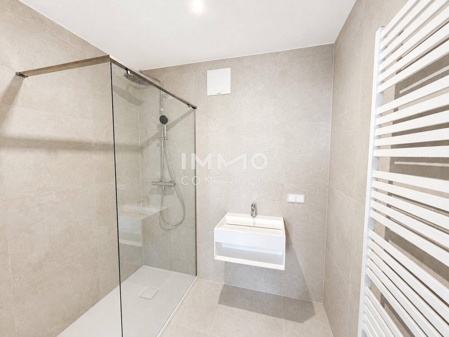 Modernes Badezimmer mit ebenerdiger Dusche, Wandwaschbecken und beheiztem Handtuchhalter.