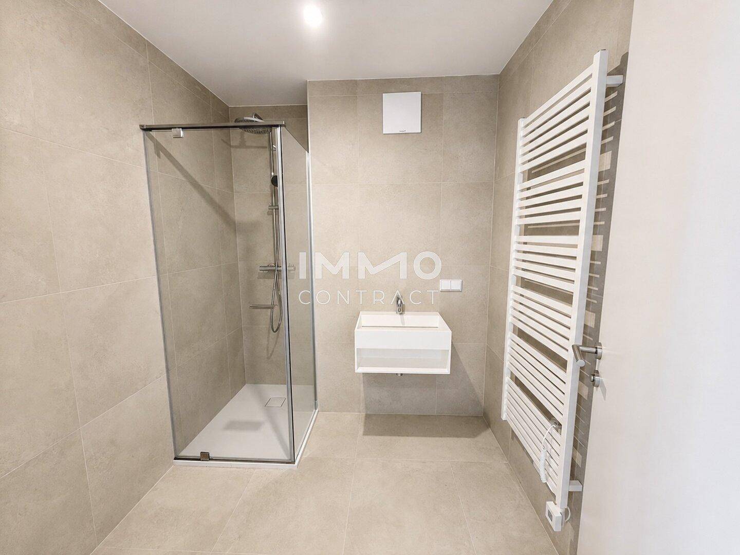 Modernes Badezimmer mit großformatigen Fliesen, begehbarer Dusche und Handtuchheizkörper.