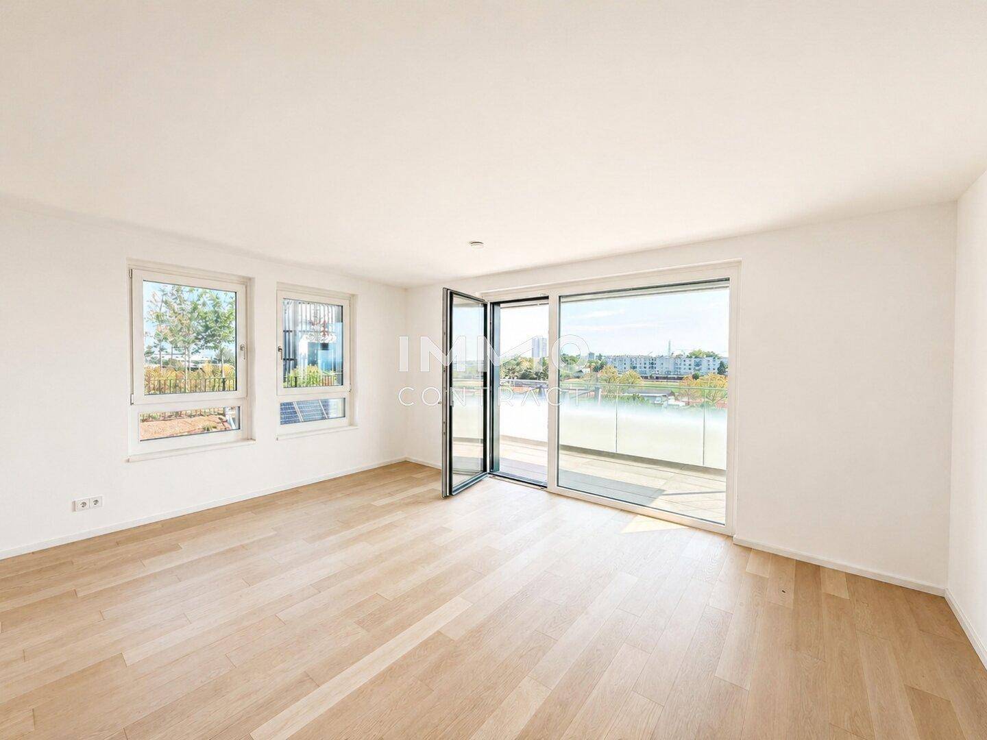 Helles Wohnzimmer mit Parkettboden, großen Fenstern und Zugang zu einem Balkon mit Wasserblick.