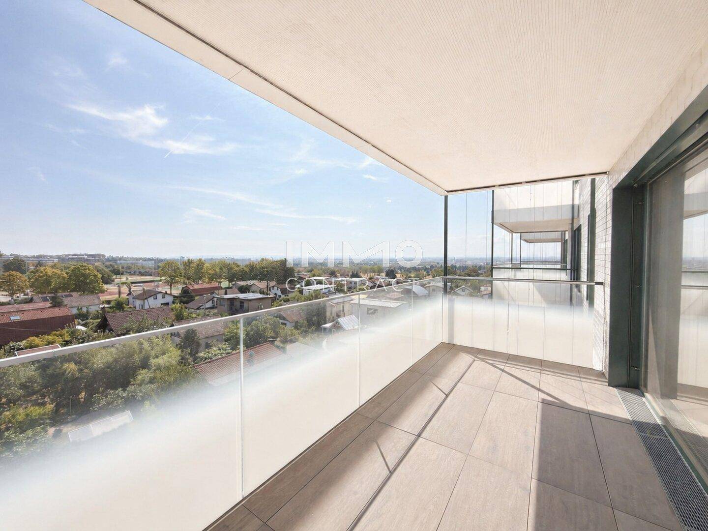 Geräumiger Balkon mit Glasbrüstung und weitem Blick über die Stadt und umliegende Bebauung.
